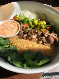 a bowl of rice with vegetables and a dipping sauce