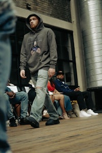 a man in a hoodie walking in front of a crowd
