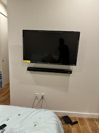 a tv mounted on the wall next to a bed