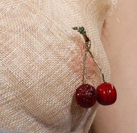 a woman's chest with a cherry brooch on it