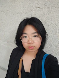 a young woman wearing glasses and a blue bag