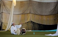 a man playing a drum in front of a curtain