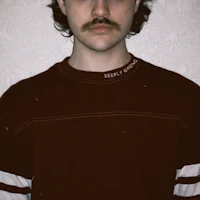 a man with a mustache wearing a maroon sweater