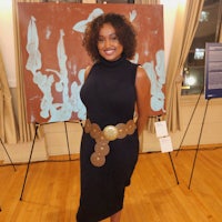 a woman in a black dress standing in front of a painting