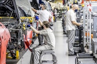 workers working on a car in a factory