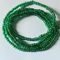 a green glass beaded bracelet on a white surface