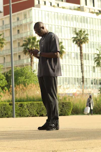 a man standing in a park looking at his cell phone