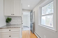 a small kitchen with white cabinets and a window
