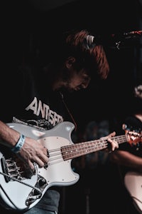 a man playing a bass guitar in front of a microphone