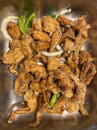 fried chicken in a metal bowl with onions and peppers