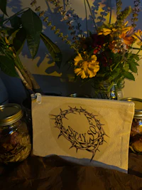 a bag with a crown of thorns on it next to a vase of flowers