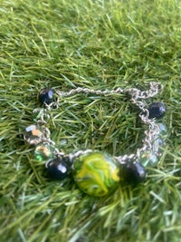 a bracelet with green and black beads on the grass
