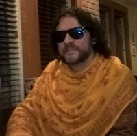 a man sitting at a table wearing sunglasses and a scarf