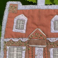 a gingerbread house ornament hanging from a tree