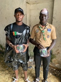 two scouts standing next to each other holding plastic containers
