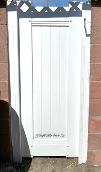 a white wooden gate in front of a brick wall
