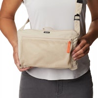 a woman holding a beige shoulder bag