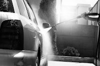 a man is washing his car with a hose