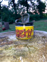 a jar with a label on it sitting on top of a tree stump