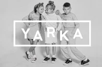 a black and white photo of three children posing in front of the word yarka
