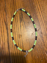 a green and brown beaded bracelet on a wooden table