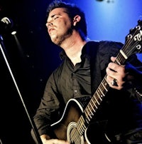 a man playing an acoustic guitar in front of a microphone
