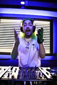 a dj with green hair in front of a mixing board