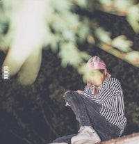 a girl wearing a striped hat sitting on top of a tree