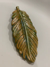 a ceramic leaf pendant on a white surface