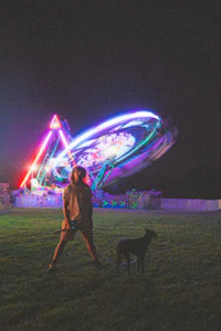 a man standing in front of a ferris wheel at night