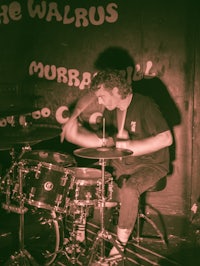 a man playing drums in front of a sign