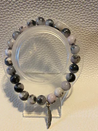 a bracelet with black and white beads and a feather