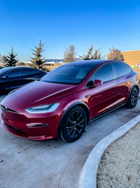 a red tesla model x parked in a parking lot