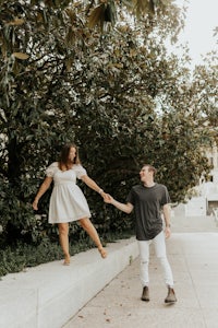 a couple holding hands in front of a tree in a park