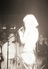 a woman singing into a microphone in front of a crowd