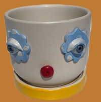 a ceramic cup with a clown face on it
