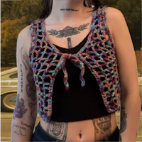 a woman wearing a crochet vest with tattoos