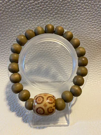 a wooden bracelet with a brown and white bead