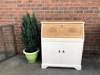 a white bureau with a potted plant next to it