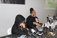 a group of people sitting at a table and making jewelry