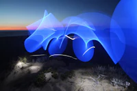 a blue light painting on the sand at dusk