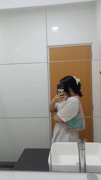 a woman taking a selfie in a bathroom mirror