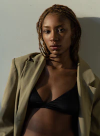 a woman in a black bikini and a tan jacket