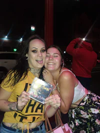 two women posing for a picture holding a cd