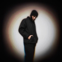 a man in a black jacket standing in front of a blurred background