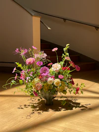 an arrangement of flowers in a vase on a wooden floor