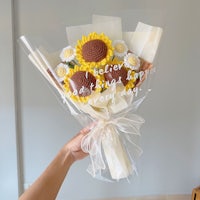 a hand holding a bouquet of sunflowers and chocolates