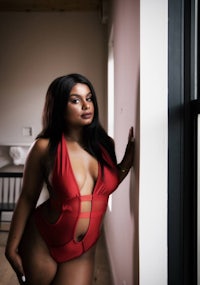 a woman in a red swimsuit posing in front of a wall
