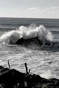a black and white photo of a person riding a wave