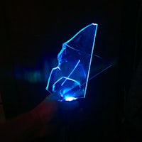 a person is holding a blue light up piece of glass